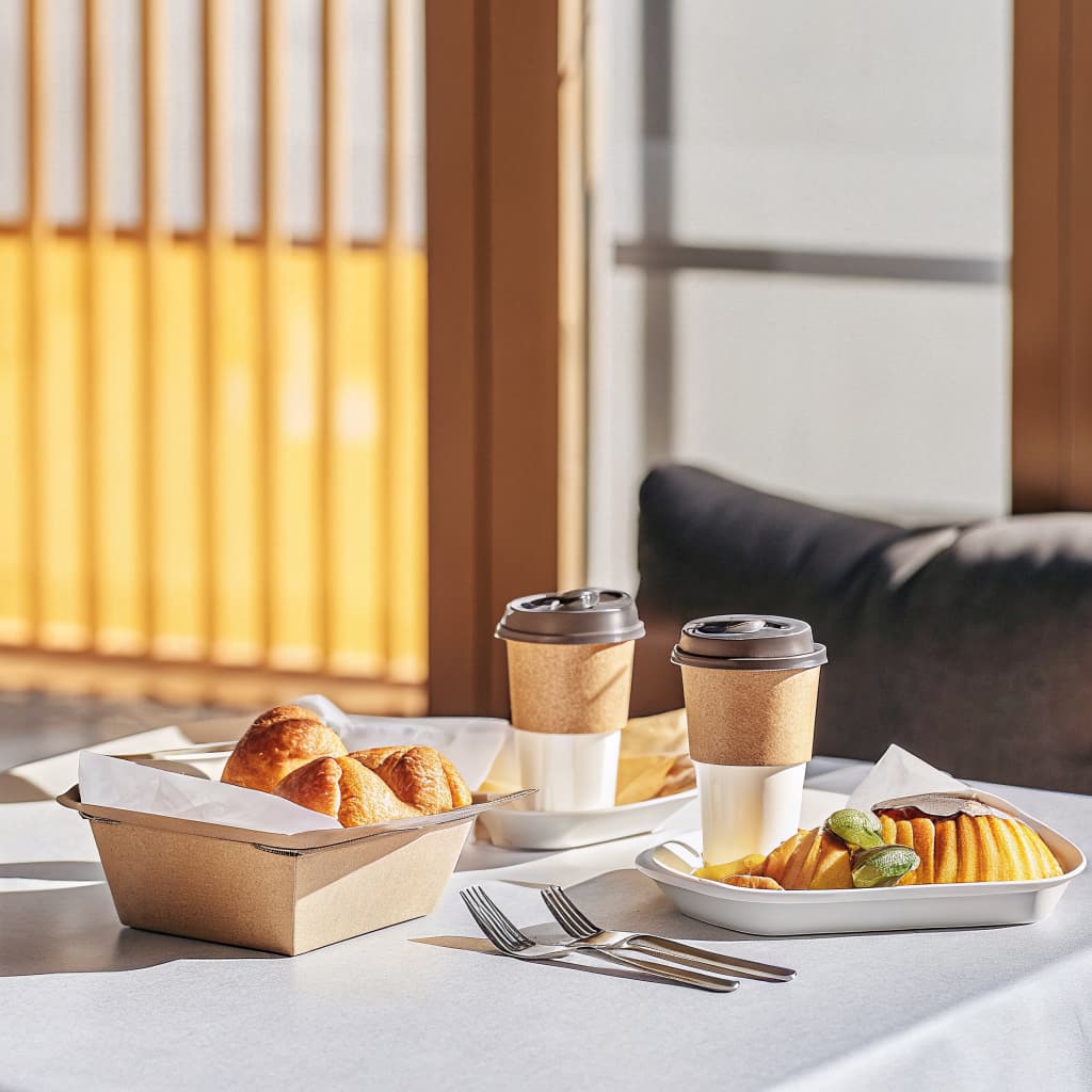 Hotel restaurant breakfast table set with compostable PHA cups and clamshell packaging