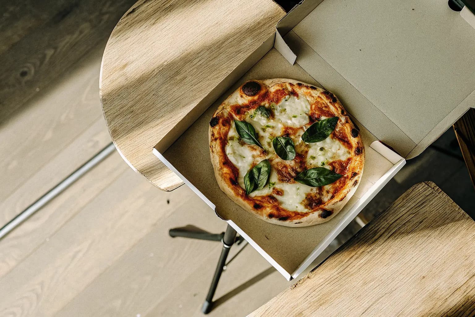 Freshly baked pizza in an open delivery box with a biodegradable PHA pizza saver tripod — sustainable pizza delivery packaging by Pure Form Solution