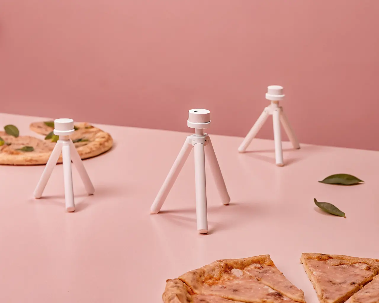 PHA biodegradable pizza saver tripods on a surface with pizza slices and green leaves — compostable drop-in replacement for conventional polystyrene pizza savers