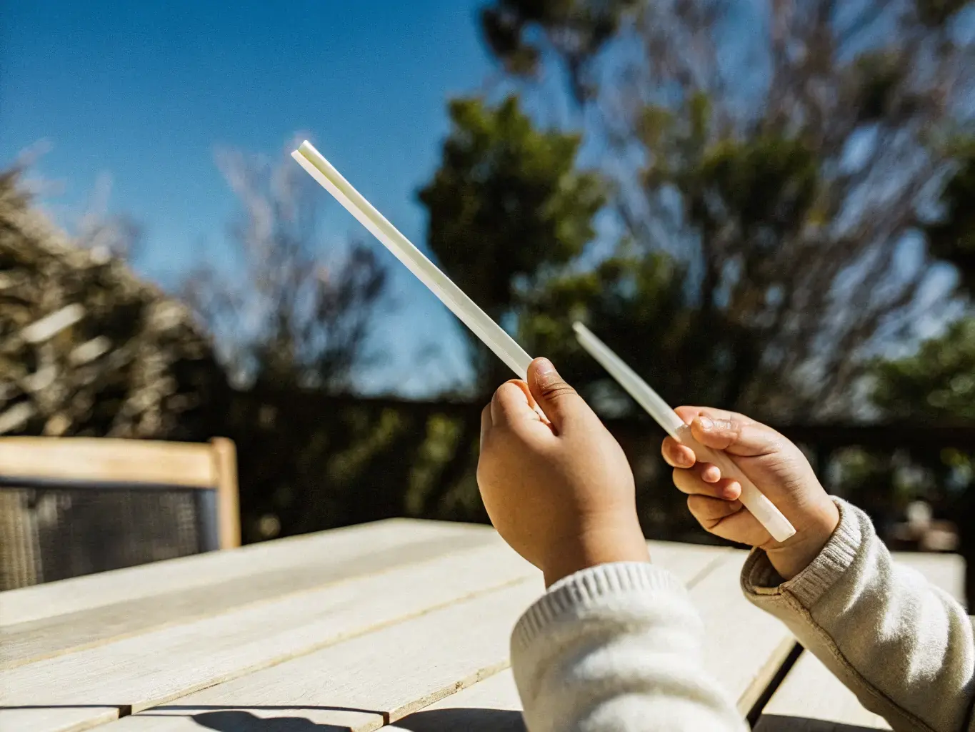 Child's hands holding a clean biodegradable PHA straw outdoors — a plastic-free future for the next generation