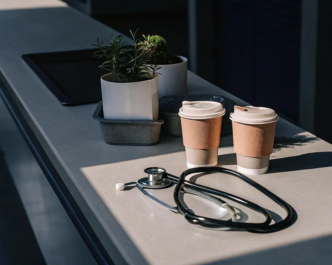 Compostable pill bottles and cups on a hospital countertop next to a stethoscope, representing a hospital sustainability program