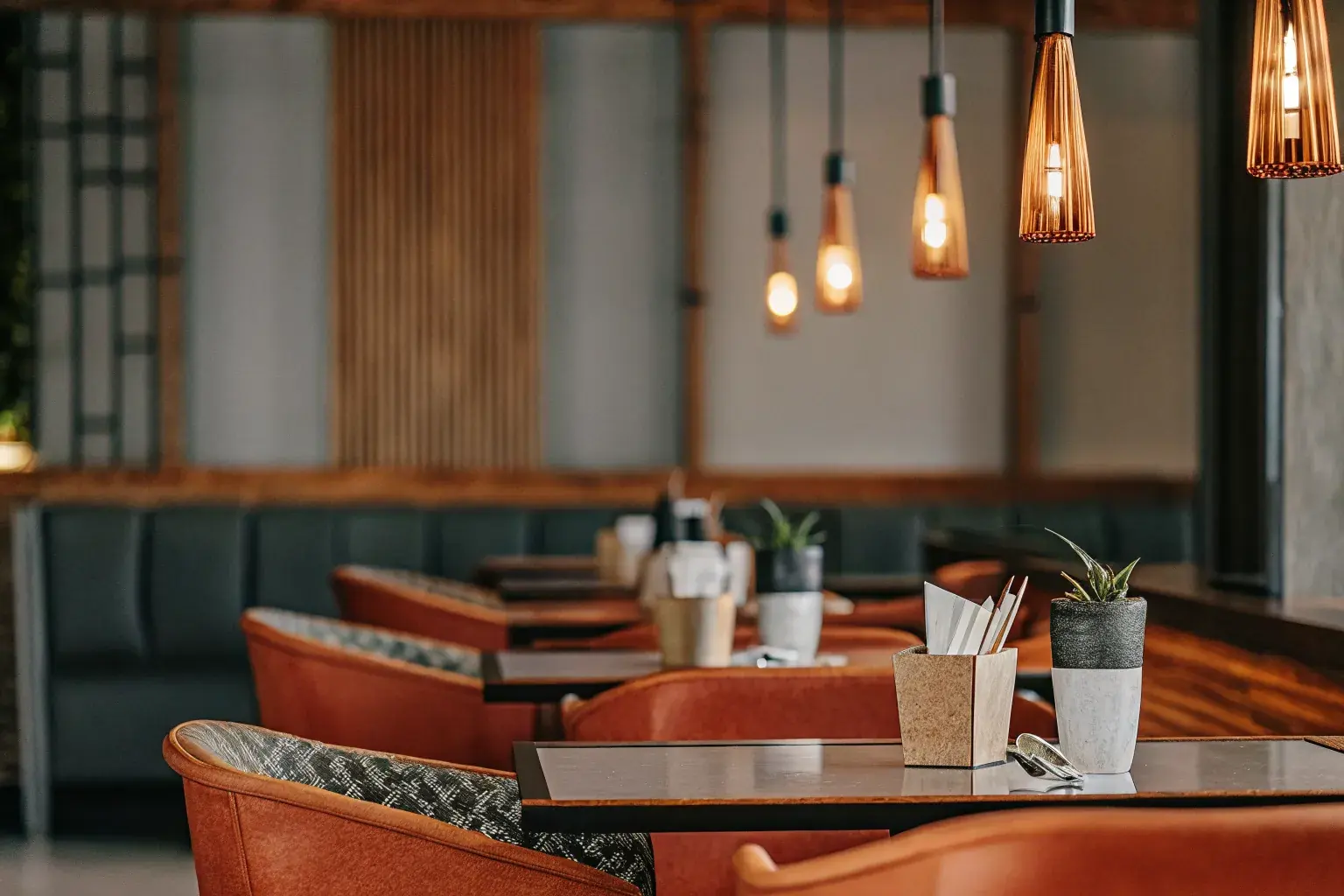 Upscale restaurant dining room with eco-friendly compostable serviceware on tables, warm Edison bulb lighting